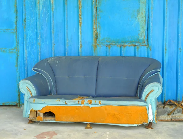 Terk edilmiş eski evin önünde mavi kanepe var. — Stok fotoğraf
