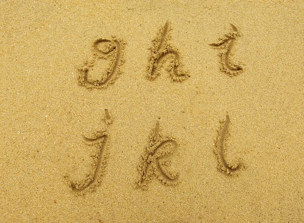 Letras do alfabeto escritas à mão em areia na praia — Fotografia de Stock