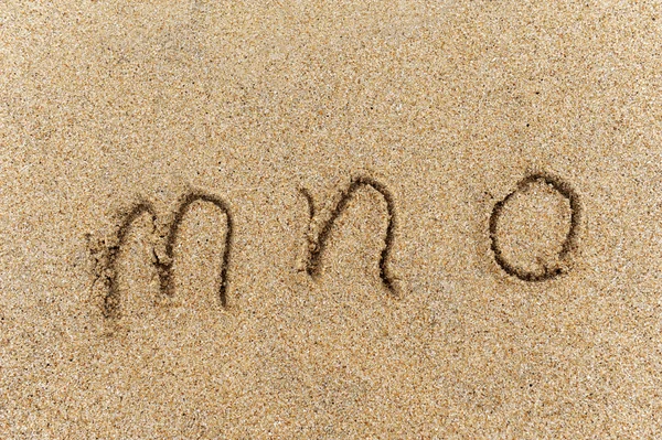 Ábécé betűk kézzel írt homok a strandon — Stock Fotó