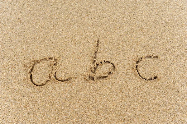 Alfabe harfleri kumsalda el yazısıyla yazılmış. — Stok fotoğraf
