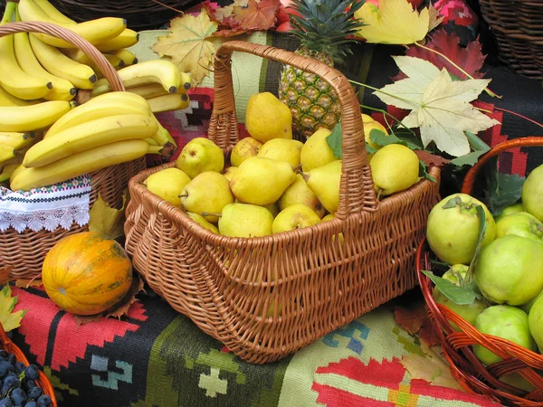 Autumnal harvest fruit in basket over carpet and leaves — Stock Photo, Image
