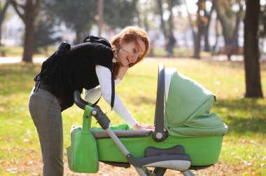 Young mother carrying baby in autumn park clipart