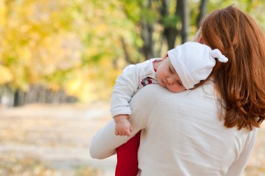 Sleeping little girl on mother's shoulder clipart