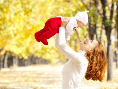 Young mother playing with daughter in autumn park clipart