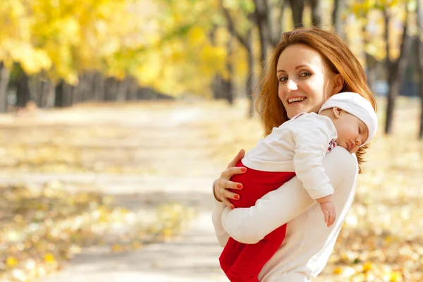 Genç anne çocuk sonbahar parkta yürüyüş ile — Stok fotoğraf