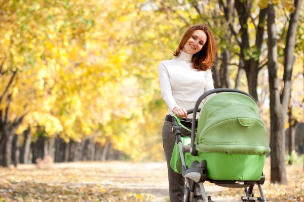 Glückliche junge Mutter mit Baby im Kinderwagen — Stockfoto