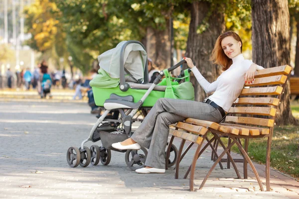 Gelukkig jonge moeder met baby in buggy — Stockfoto