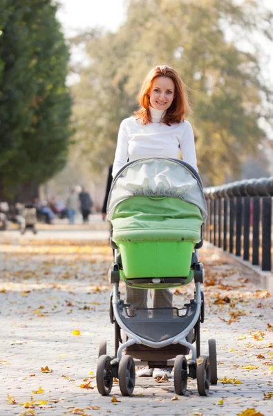 Glad ung mamma med bebis i barnvagnen — Stockfoto