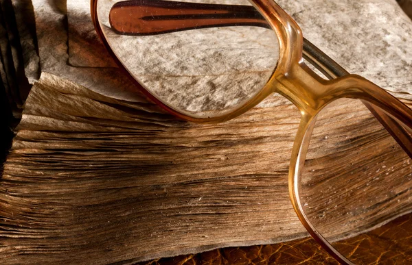 Antique glasses on old weathered book — Stock Photo, Image