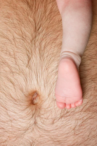 Babybein auf dem Bauch des Vaters — Stockfoto