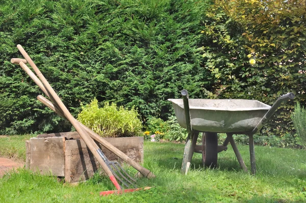 Velho carrinho de mão e ferramentas de jardinagem — Fotografia de Stock