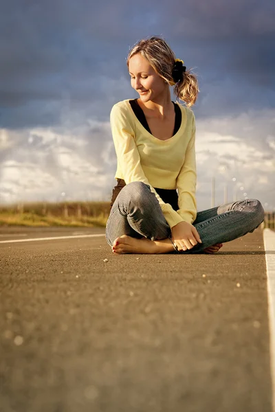 Female teen sits in the middle of the highway — Stock Photo, Image