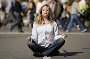 Woman meditating in busy urban street clipart