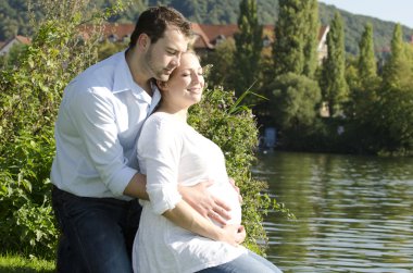 Pregnant couple hugging clipart