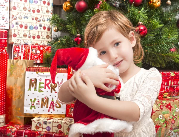 Дитина з лялькою Санта перед ялинкою — стокове фото