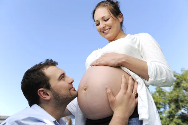 Чоловік цілує вагітний живіт своєї дружини — стокове фото