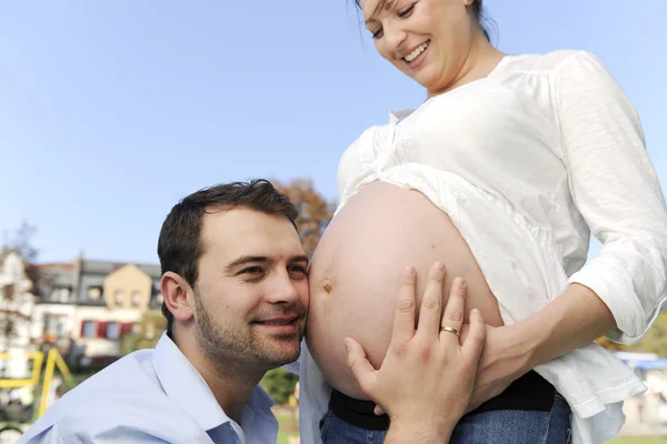 Mari écoutant bébé dans le ventre enceinte — Photo