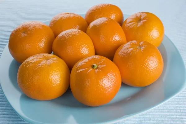 Ripe fresh tangerine on blue plate — Stock Photo, Image
