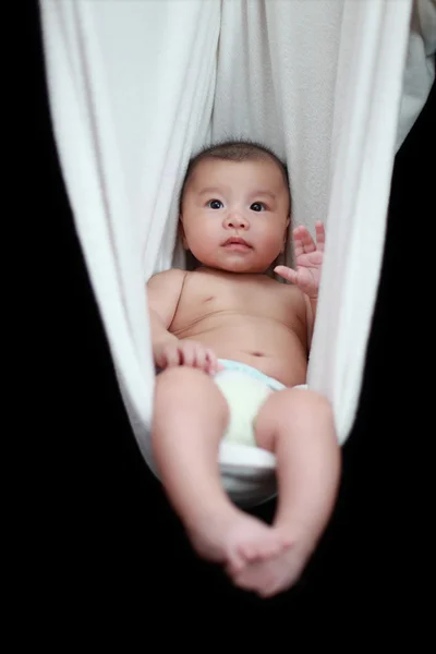 裸で寝ている赤ちゃんが黒の背景上に分離されて白いハンモック スリング. — ストック写真