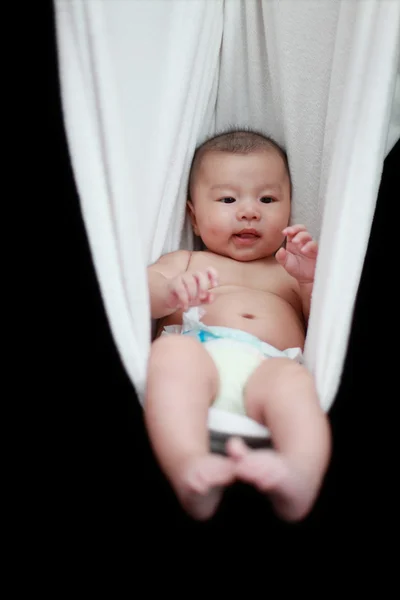 裸で寝ている赤ちゃんが黒の背景上に分離されて白いハンモック スリング. — ストック写真