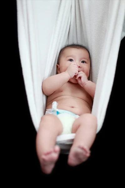 Bebé desnudo durmiendo en el cabestrillo blanco de la hamaca, aislado en un fondo negro . —  Fotos de Stock