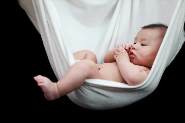 Nacktes Baby schlafend in weißen Hängemattenschlingen, isoliert auf schwarzem Hintergrund. — Stockfoto
