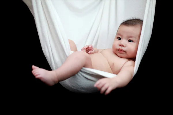 Bambino nudo che dorme nell'imbragatura bianca del hammock, isolato su uno sfondo nero . — Foto Stock