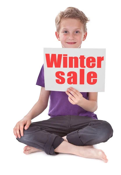 Menino segurando página branca com palavra venda de inverno — Fotografia de Stock