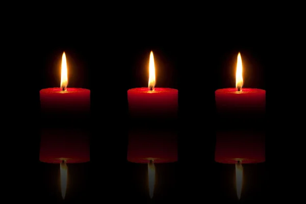 三烧红蜡烛在黑色的背景 — 图库照片