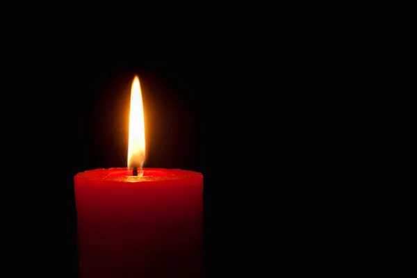 Brennende rote Kerze vor schwarzem Hintergrund — Stockfoto