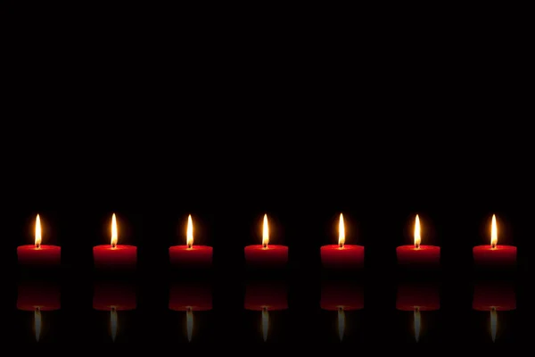 Queimando velas vermelhas na frente do fundo preto — Fotografia de Stock