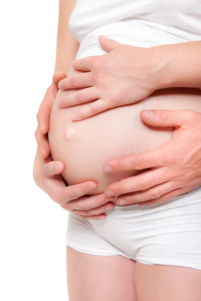 Cztery ręce trzymając brzuch kobiety w ciąży — Zdjęcie stockowe