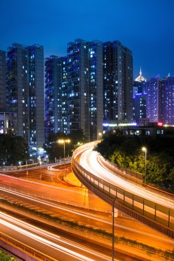 Light trails on the viaduct in bustling city at night clipart