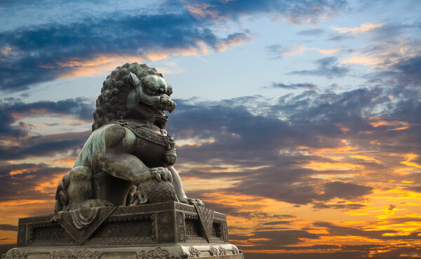 Величественная статуя льва на фоне заката
