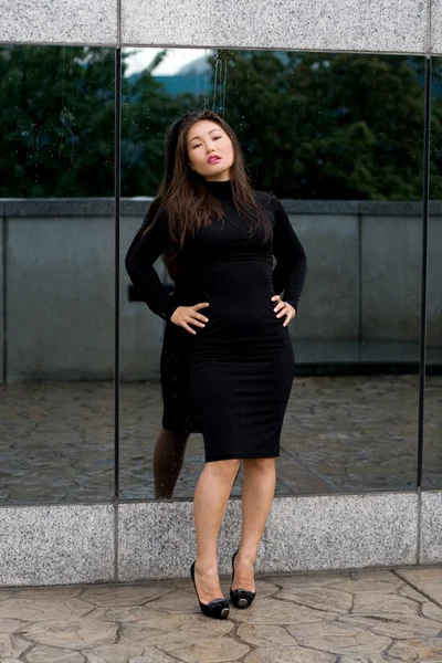 Сексуальная девушка в черном платье стоит перед зеркалом — стоковое фото