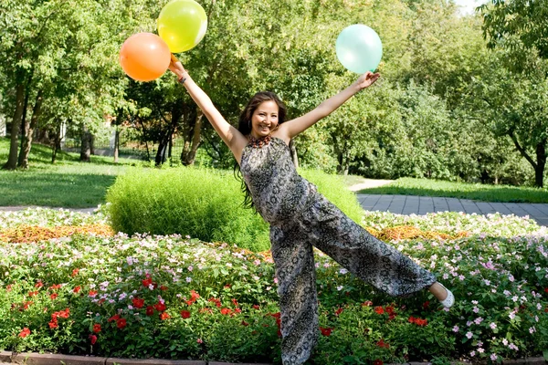 Menina grávida alegre com balões coloridos andando no parque — Fotografia de Stock