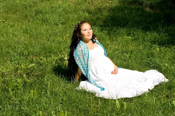 Schöne schwangere Mädchen sitzt auf Gras — Stockfoto