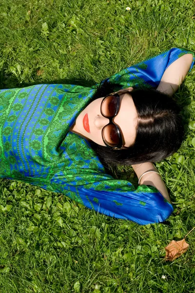 Dívka ležící na trávě v parku — Stock fotografie