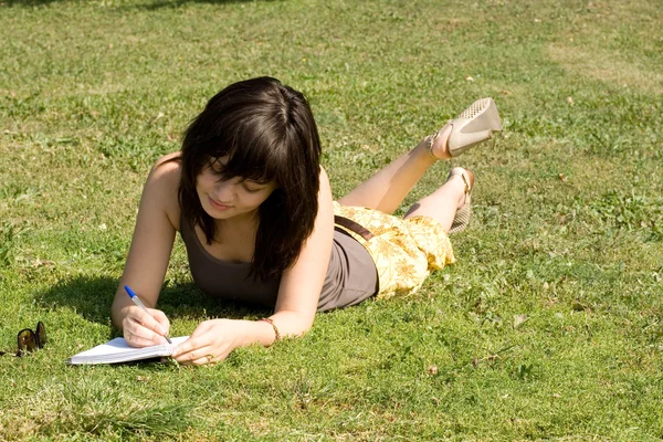 Meisje liggend op gras in park — Stockfoto