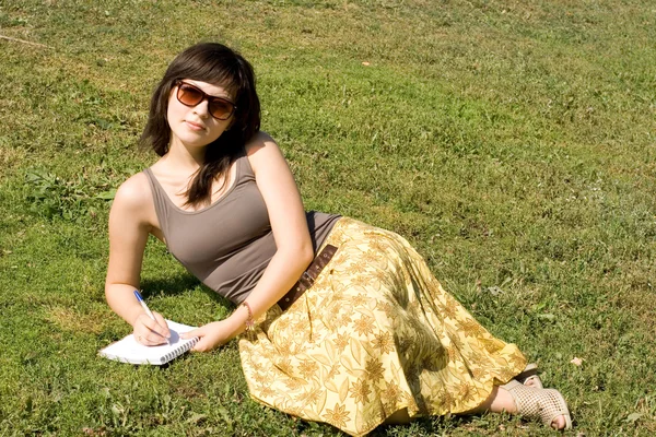 Dívka sedící na trávě v parku — Stock fotografie