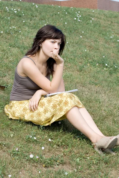 Девушка сидит на траве в парке — стоковое фото