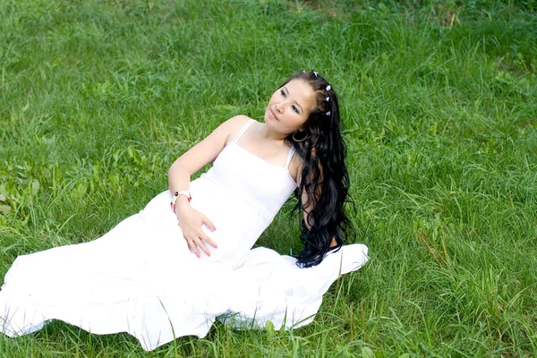 美丽的怀孕女孩坐在草地上 — 图库照片