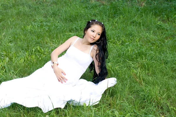 잔디에 앉아 아름 다운 임신한 여자 — 스톡 사진