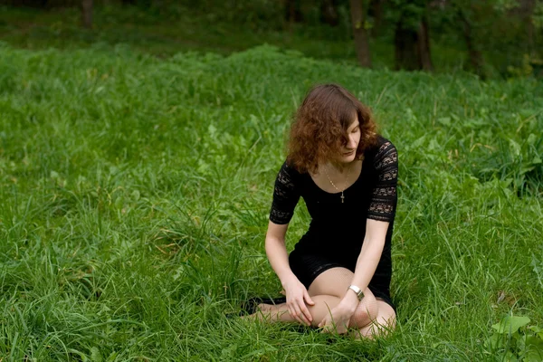 Vacker flicka sitter på gräset — Stockfoto