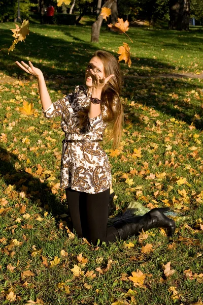 Uśmiechnięte dziewczyny rzucanie liści w parku jesień — Zdjęcie stockowe