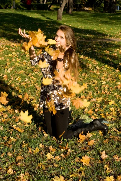 Smiling girl throwing leaves in autumn park — Stock Photo, Image
