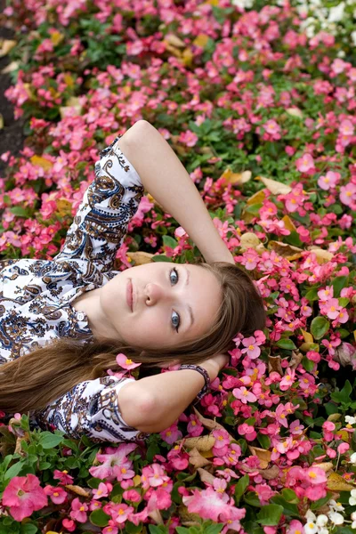 Hermosa chica acostada entre flores —  Fotos de Stock