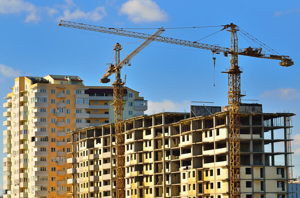 Tower cranes on building of the many-storeyed house
