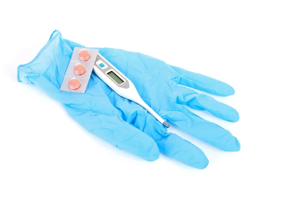 Медицинская перчатка с таблетками и термометром — стоковое фото