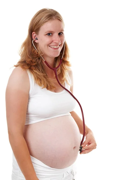 Mother is listening with stethoscope on pregnant belly — Stock Photo, Image